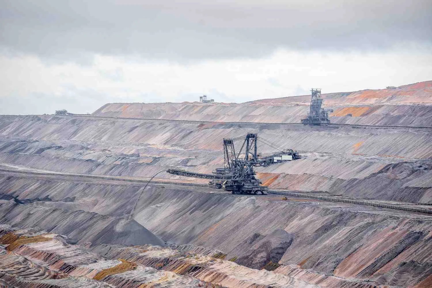 Large open-cast mining excavator on terraced pit walls